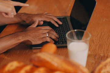Handsome man sitting near his wife at kitchen. Family couple see social media, surf the web while sitting at kitchen table with generic laptop. Couple working with laptop at home