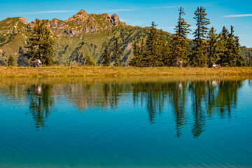 Alpine summer view with reflections and hikers at Lake Spiegelsee, Mount Fulseck, Dorfgastein, St. Johann im Pongau, Salzburg, Austria