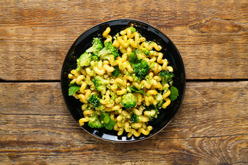 Plate of tasty pasta with broccoli on wooden background