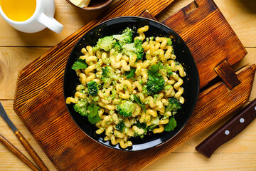 Plate of tasty pasta with broccoli on wooden background
