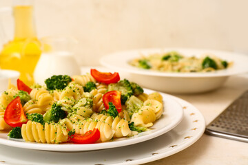 Plates of tasty pasta with broccoli and tomatoes on white background
