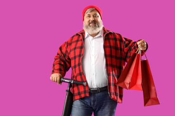 Mature man with shopping bags and electric scooter on purple background