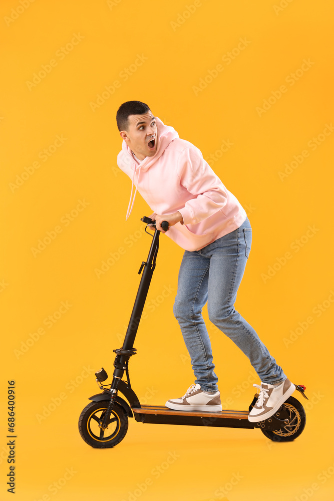 Sticker Shocked young man riding electric scooter on yellow background