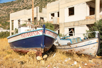 Fototapeta na wymiar Plaka, Crete, Greece - September 23rd 2023 - Abandoned boats in a backstreet parking lot in Plaka, Crete.