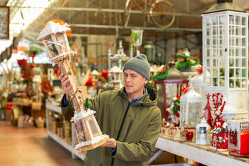 Positive customer carefully choosing Christmas lantern in a household goods store