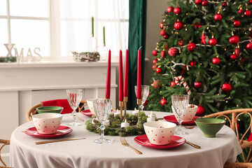 Festive table setting with candles and Christmas decorations in dining room