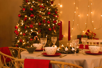 Festive table setting with candles and Christmas decorations in dining room at evening