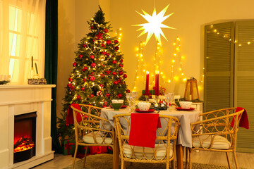 Interior of festive room with Christmas tree, decorations, fireplace and served dining table at evening