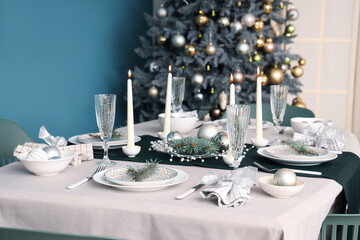 Festive table setting with burning candles and Christmas decorations in dining room