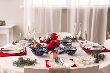 Festive table setting with wine glasses and Christmas decorations in dining room