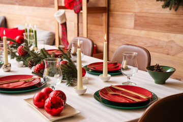 Festive table setting with Christmas decorations and burning candles in dining room, closeup