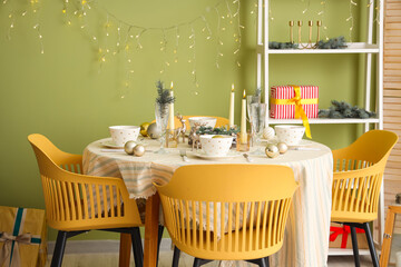 Festive table setting with Christmas decorations, reindeers and burning candles in dining room