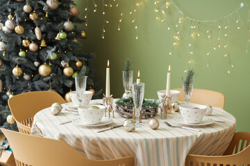 Festive table setting with Christmas decorations, reindeers and burning candles in dining room
