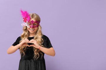 Cute little girl wearing carnival mask and making heart with her hands on lilac background