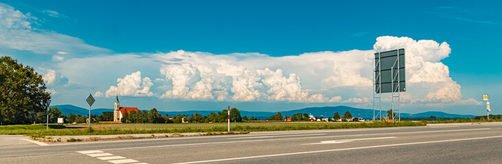 Storm clouds above the Bavarian forest on a sunny summer day with a church seen from...