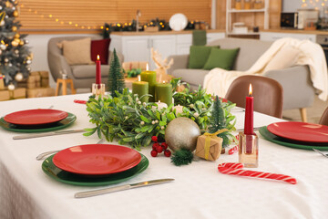 Festive table serving with mistletoe wreath, burning candles and Christmas decorations