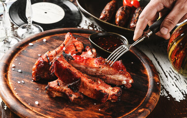 Hands cut barbecue pork spare ribs with hot honey chilli marinade on wooden cutting board with...