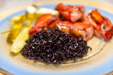 Traditional rustic Brazilian food, black rice, smoked pork ribs and pickles