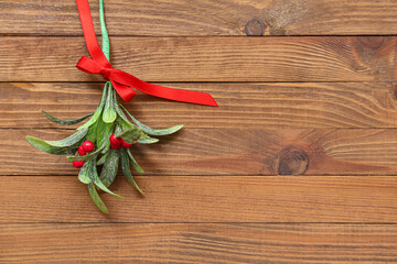 Mistletoe branch with ribbon on wooden background