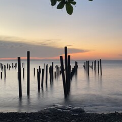Watching the sunset over the posts of an old pier in the sea of Miches, Dominican Republic