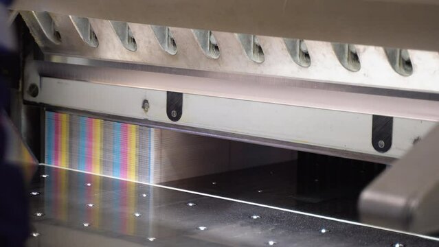 Worker cutting paper using paper cutting machine in a printing factory. Printing cutting machine, final cut