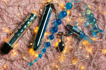 Sex toys with Christmas tree garland on pink fluffy carpet