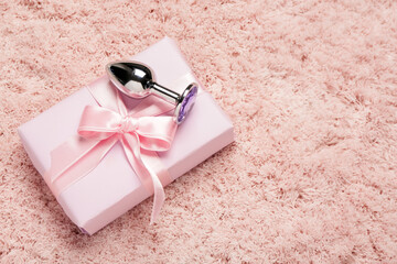 Anal plug with Christmas gift on pink fluffy carpet