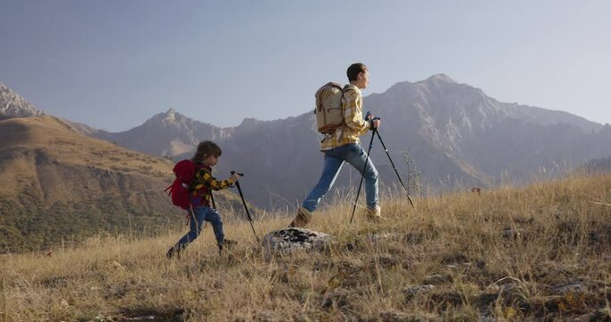 Mother and son conquer mountain, trekking poles backpacks. Satisfaction of reaching new heights, brave mother and son conquer summit, healthy lifestyle and wonders of ecotourism. Cinematic, family