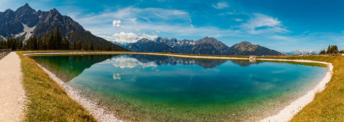 High resolution stitched alpine summer panorama with reflections in a lake at Serles cable car...