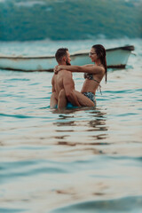 Fototapeta premium A romantic young couple sharing a passionate kiss amidst the serene beauty of the ocean at sunset.