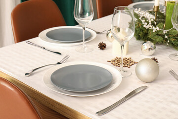 Festive table setting with clean plates, wine glasses and Christmas decorations, closeup