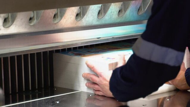 Worker cutting paper using paper cutting machine in a printing factory