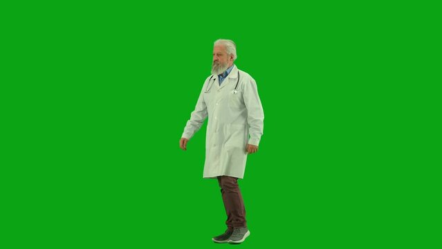 Portrait of aged man medic on chroma key green screen. Senior doctor in white coat walking and looking around, making rounds in hospital.