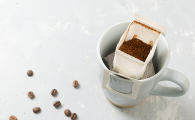 The process of brewing a bag Drip coffee into a cup on a gray background. A quick way to prepare a tasty and aromatic drink. Horizontal orientation. Selective focus. Copy space