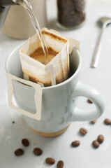 The process of brewing a bag Drip coffee into a cup on a gray background. A quick way to prepare a tasty and aromatic drink. Vertical orientation. Selective focus
