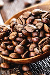 rustic wooden spoon with roasted arabica coffee beans, scattered on the table. Cappuccino coffee preparation