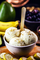 vegan banana ice cream made with frozen bananas and tropical fruits in the background, without adding chemicals. Healthy dessert.