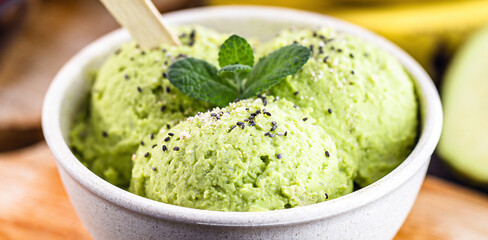 Homemade organic green avocado ice cream ready to eat, with mint leaf decorating.