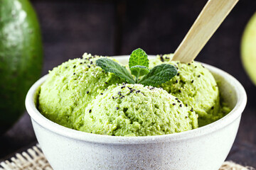 Homemade organic green avocado ice cream ready to eat, with mint leaf decorating.