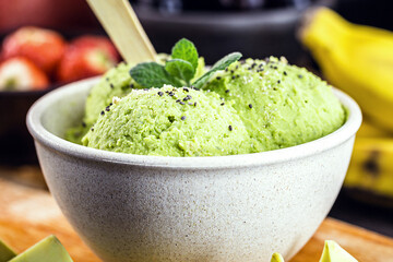 Homemade organic green avocado ice cream ready to eat, with mint leaf decorating.