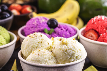 vegan ice cream made with organic fruits, with tropical fruits in the background, flavors of strawberry, banana, jabuticaba and avocado
