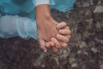 Close up photo the hands of a romantic couple are intimately entwined beneath the water's surface,...