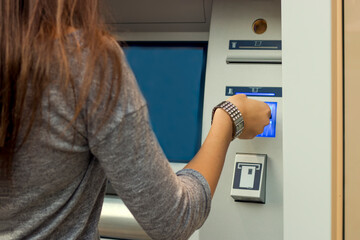 At the ATM. Attractive long haired brunette with shopping bags using automated teller machine