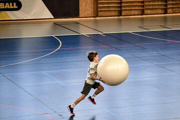 Énergie Sportive, jeune handballeur dribblant avec une grosse balle en plein élan