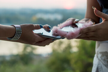 Close up view of two female hands using smartphone near the river during sunset