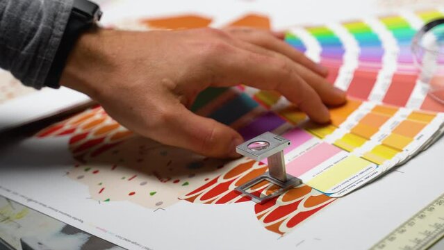 Color management in print production. Worker checking print quality of graphics
