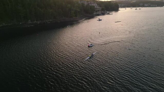 Team rowing on calm ocean water early in the morning Aerial view.