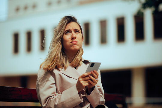 Stressed Woman Checking her Phone Waiting on a Bench. Bored girlfriend waiting for her blind date in the park
