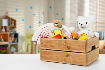 Wooden crate with many different toys on white table in kindergarten. Space for text