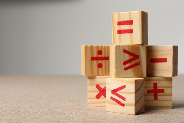 Wooden cubes with mathematical symbols on table against light background. Space for text